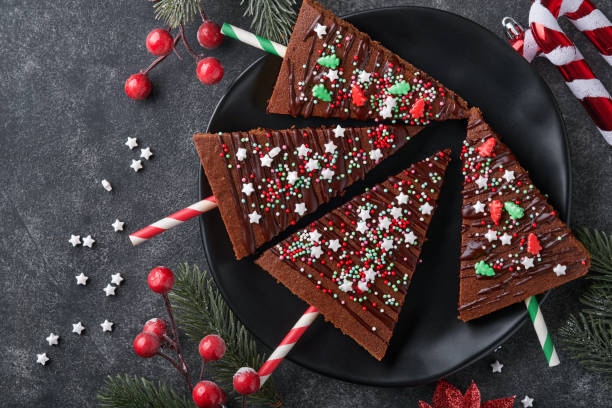 istock Chocolate brownies Christmas tree with chocolate icing and festive sprinkles on stone table. Christmas food ideas sweet homemade Christmas holidays pastry concept. Holiday cooking concept. Top view. 1443302171
