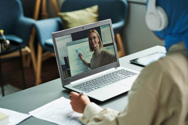 istock Confident blond teacher on laptop screen pointing at whiteboard 1443305370
