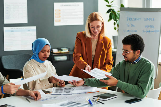 istock Group of students taking grammar tests while teacher passing papers to them 1443305442