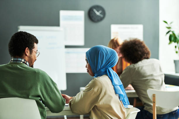 Back view of two young intercultural students discussing new subject