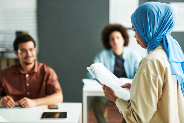 istock Young Muslim teacher in blue hijab looking at text in document 1443305474