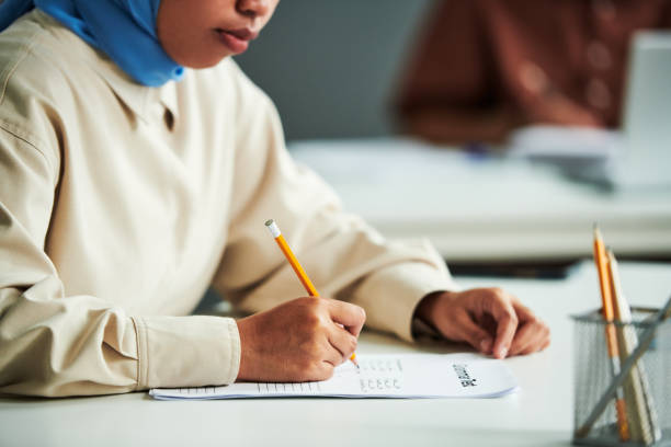 Hand of young Muslim female student with pencil stock photo
