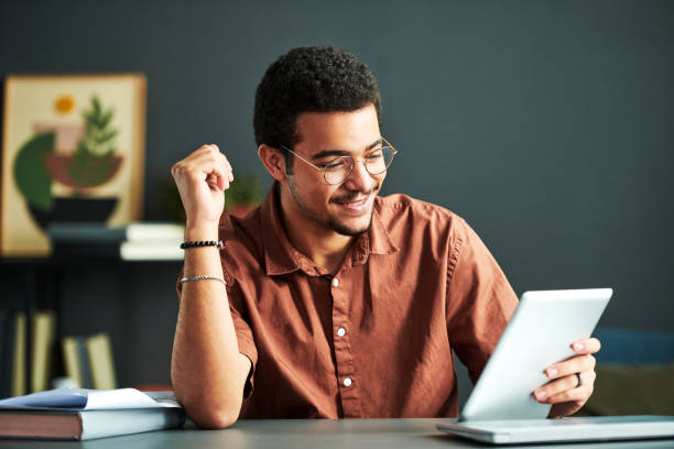 istock Young smiling student of online course of study looking at tablet screen 1443305506