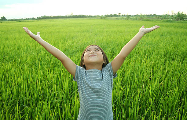 Young girl expressing joy in a field of long grass Happy girl having good time. arms outstretched photos stock pictures, royalty-free photos & images