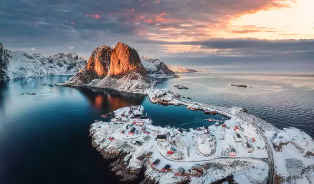 Beautiful landscape of aerial view of snowy mountain and fishing village on coastline in winter at Lofoten Islands, Norway