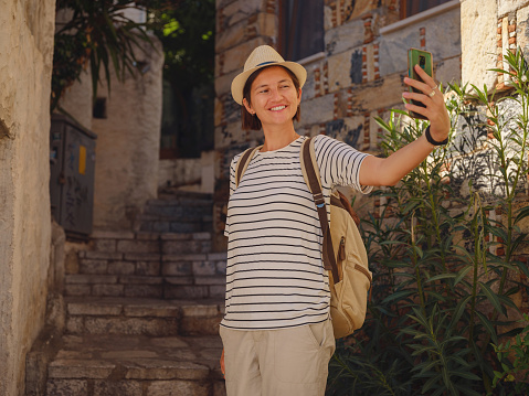 Marmaris is resort town on Turkish Riviera, also known as Turquoise Coast. Marmaris is great place for sailing and diving. Tourist Woman on Beautiful Streets of old Marmaris taking selfie on smartphone.
