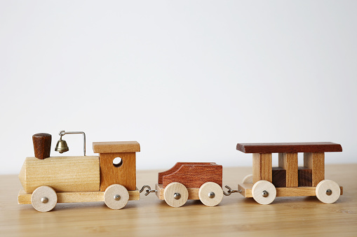 Wooden toy train with one carriage on wooden table with white background and copy