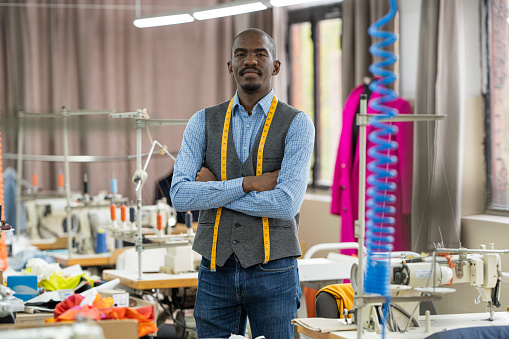 Portrait of african american tailor man, looking at the camera smiling in atelier studio