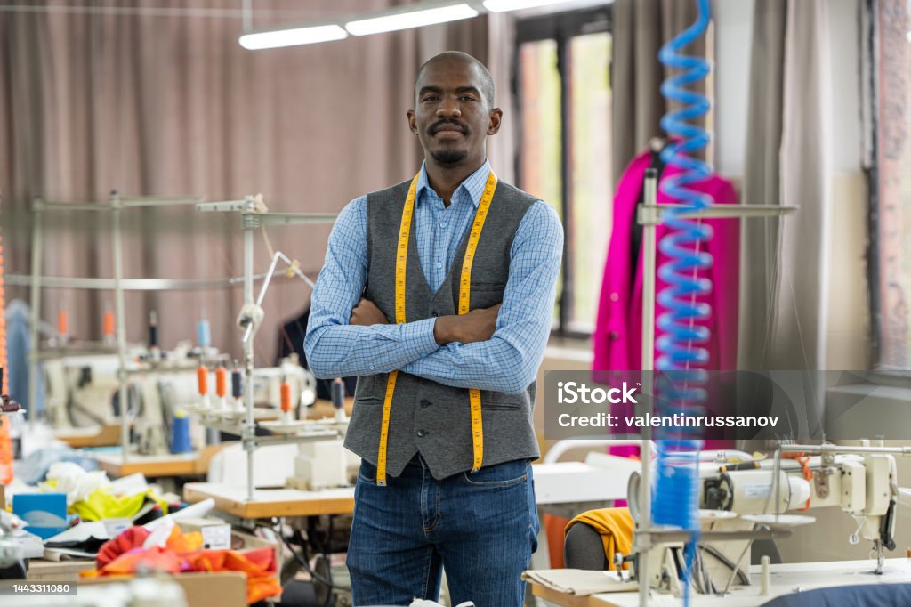 Portrait of african american tailor man, looking at the camera smiling in atelier studio Tailor Stock Photo
