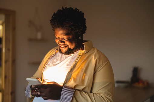Overweight plus size american african male smiling and texting in smartphone