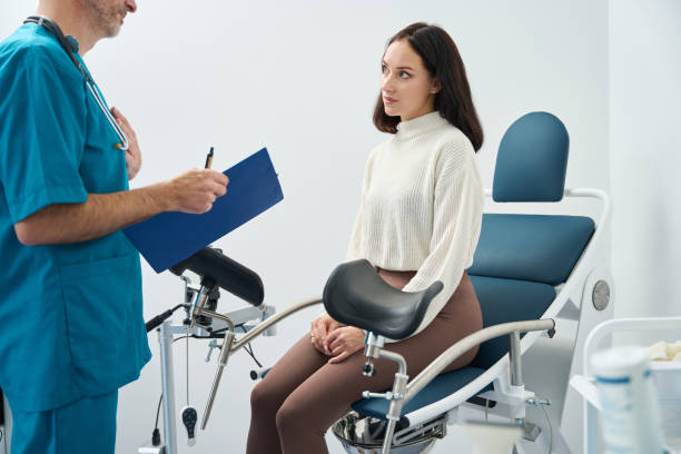 Woman sits on medical chair and listens to a doctor stock photo