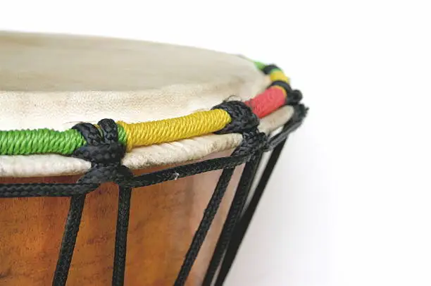 Close up of drum detail on white background.  Includes all components of the drum including rope (black, red, green, yellow), wood, knots, goat skin.  Purchased in Kenya from local artisan.