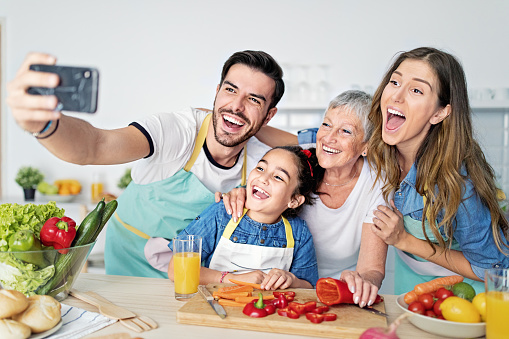 Happy family is taking selfie/making video call together in a kitchen