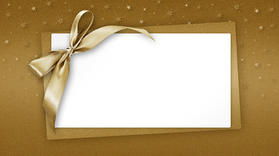Christmas Blank gift greeting card ticket with shiny golden ribbon bow, isolated on beige background with sparkle stars, top view white copy space template for promotion shopping advertising banner