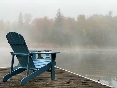 Blue Muskoka / Adirondack Chair on dock on a foggy fall morning in cottage country in Ontario