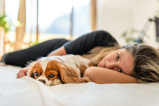 Adult woman lying in bed with her dog