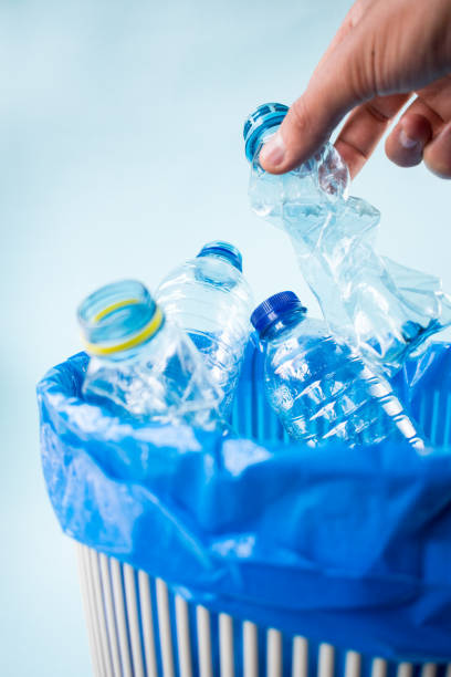 istock Man leaving a plastic bottle in a blue recycling bin 1443316668