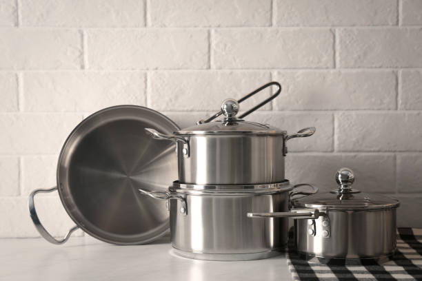 istock Set of stainless steel cookware on table near white brick wall 1443317295