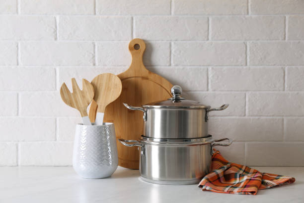 istock Pots and kitchen utensils on table near white brick wall 1443317895