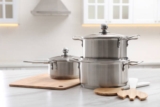 istock Set of stainless steel cookware and kitchen utensils on white table indoors 1443317898