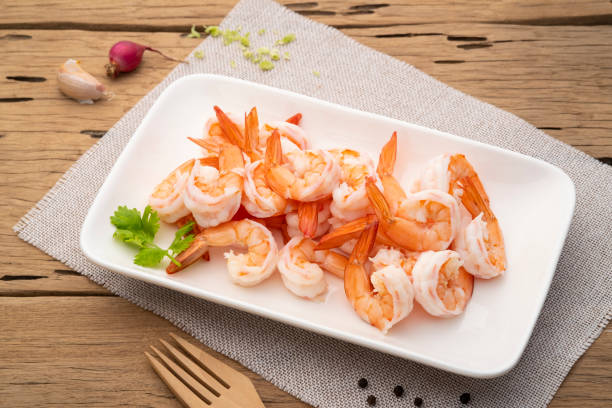 Cooked metapenaeus shrimp with lemon and broccoli on a wooden table