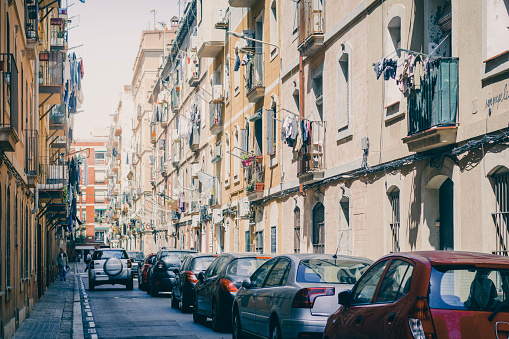 Street of a European city, full of cars parked on the side of the road on a summer day. o