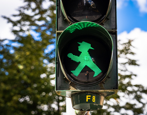 Berlin, Germany - Close-up on an illuminated green walk symbol, as a Ampelmännchen, with this symbol traditionally used as a traffic light signal in East Germany.