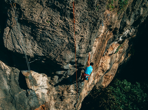 Aerial view of young man doing extreme sport rock climbing in mountains of Taiwan