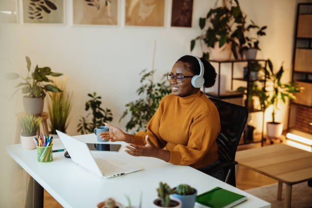 imprenditrice africana che lavora da un ufficio verde, con videochiamata con partner e colleghi remoti - conferenza via web foto e immagini stock