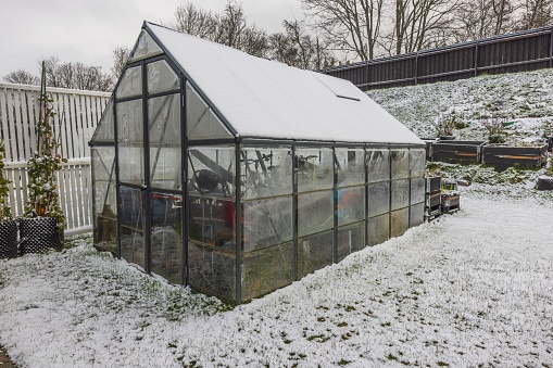 Beautiful winter view of garden plot in house with greenhouse and things put away for winter. Sweden.