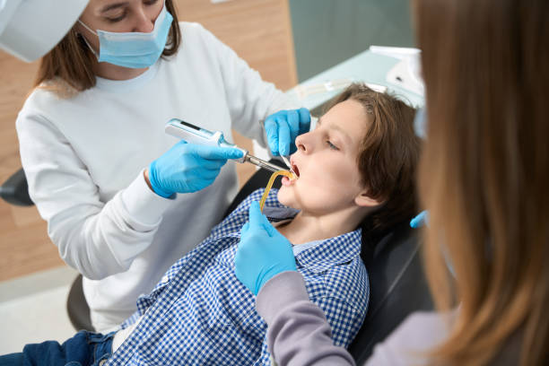 Woman dentist at the workplace treats tooth to a boy stock photo