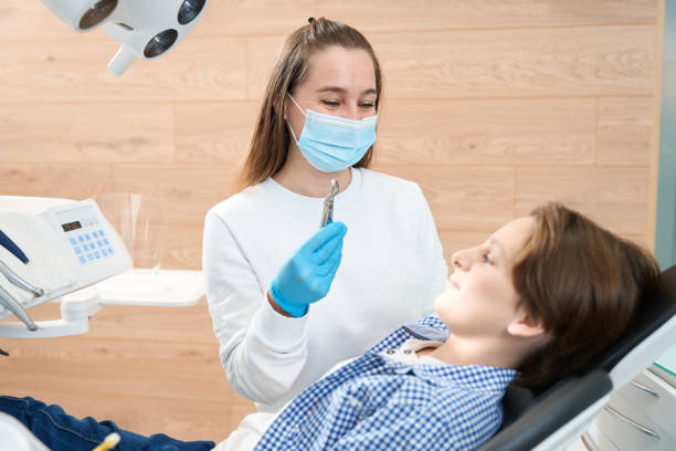 Smiling female dentist showing boy special tool for tooth extraction