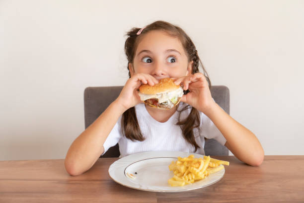 istock Little girl eating a big burger 1443326421