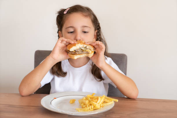 istock Little girl eating a big burger 1443326619