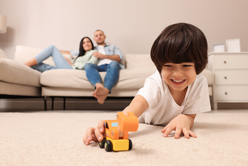 Child playing with toy and parents working at home