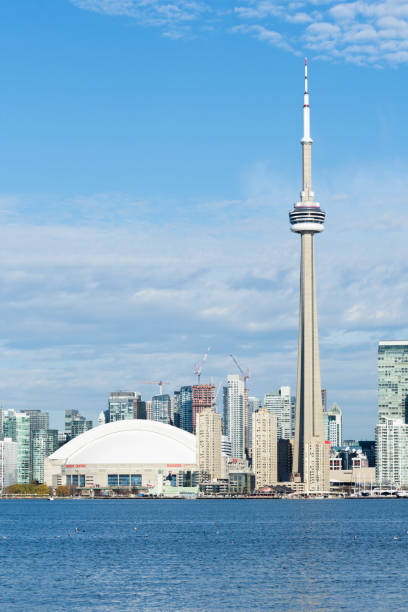 Toronto, Ontario, Canada – October 2014: Ground-level views of the CN Tower and surrounding skyscrapers in downtown Toronto, including the Rogers Centre and high-rise buildings under a clear autumn sky.