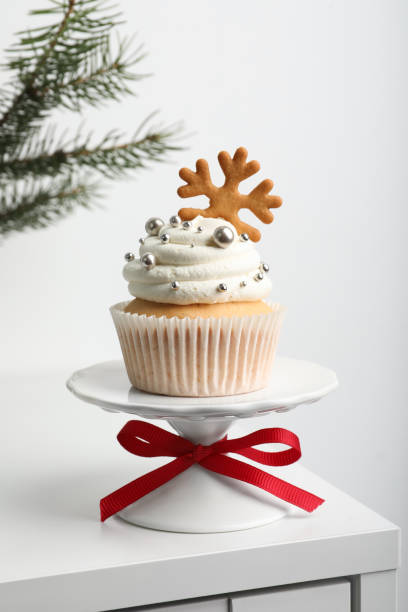 istock Tasty Christmas cupcake with cream and snowflake cookie on white table 1443327497