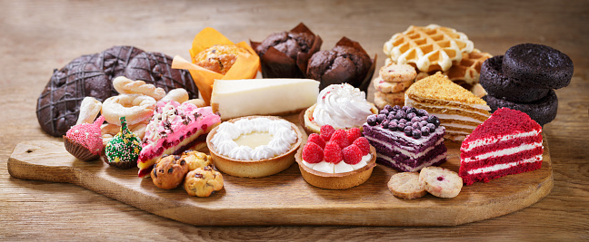 Sweet dessert. Various piece of cakes, muffins and cookies on wooden board