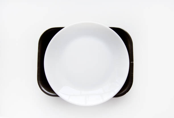 istock White porcelain plate on a black backing on a white background. Dishes on black material. A white plate. 1443330478