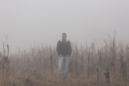 Farmer looking at his ruined plants in corn agricultural fields