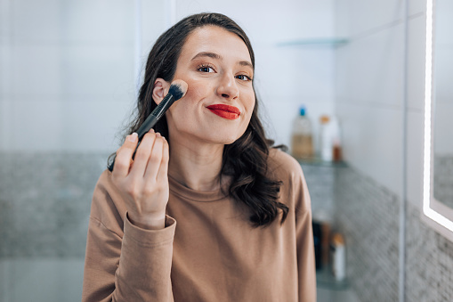 Calm woman, face and brushes for makeup, beauty or cosmetics against a pink studio background. Female person or model with cosmetic tools, brush or equipment for grooming or applying facial treatment