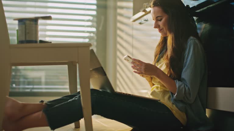 SLO MO Young woman uses her laptop and smartphone to find information for the renovation of the chair