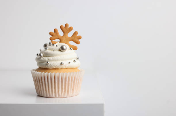 istock Tasty Christmas cupcake with cream and snowflake cookie on white table, space for text 1443332928