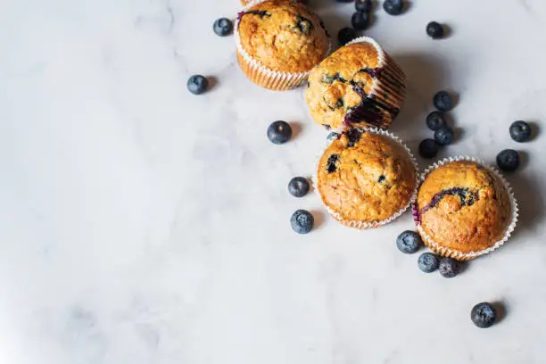 Photo of Blueberry muffins on a white marble background.