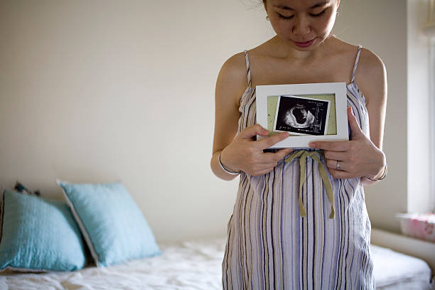 Pregnant Woman Holding Ultrasound Picture Pregnant Woman Holding Ultrasound Picture water birth photos stock pictures, royalty-free photos & images