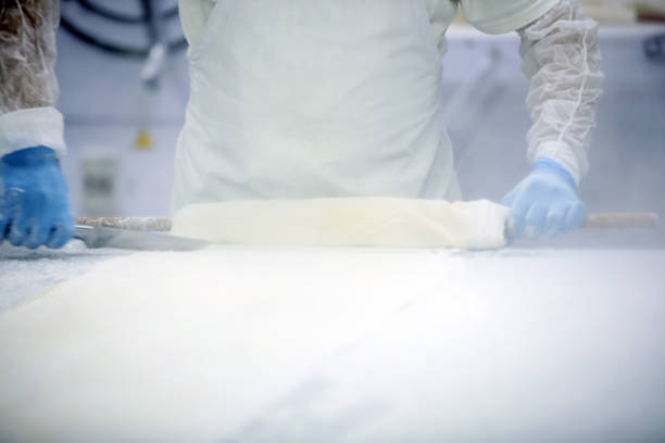 Bakery.A bakery worker places trays with raw bread in the oven. Industrial production of bakery products.