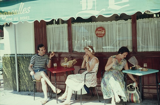 Cote d'Azur (exact location unknown), southern France, 1958. Holidaymakers are sitting at small tables in front of a southern French street cafe and eating a sandwich.