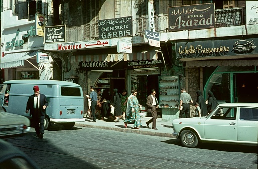 Beirut, Lebanon, 1965. Street scene with shops, advertising signs, pedestrians and vehicles in Beirut.