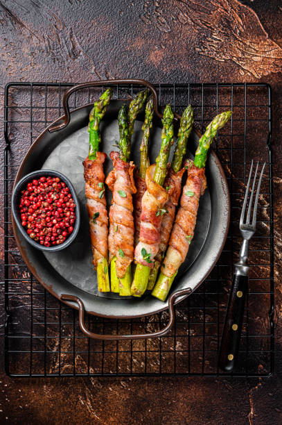 Baked Prosciutto wrapped green asparagus. Dark background. Top view