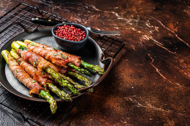 istock Baked Prosciutto wrapped green asparagus. Dark background. Top view. Copy space 1443342411